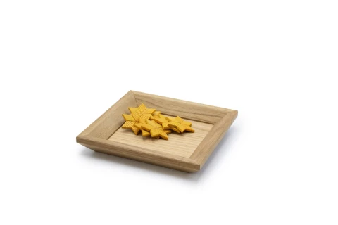 Holztablett aus hellem Holz mit rechteckiger Vertiefung, darin mehrere gelbe, sternf&ouml;rmige Geb&auml;ckst&uuml;cke mit geriffelter Oberfl&auml;che. Das Tablett steht auf wei&szlig;em Hintergrund.