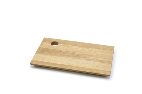 Rechteckiges Schneidebrett aus hellem Holz mit sichtbarer Maserung, eine abgeschr&auml;gte Kante an der Unterseite und eine kreisrunde Aussparung in der oberen linken Ecke.